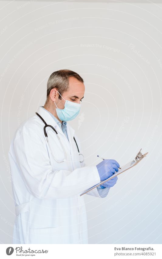 Porträt eines kaukasischen Arztes mit Schutzhandschuhen und Maske. Arbeiten an einem Ordner. Chinesisches Corona-Virus-Konzept. 2019-nCoV Mann professionell
