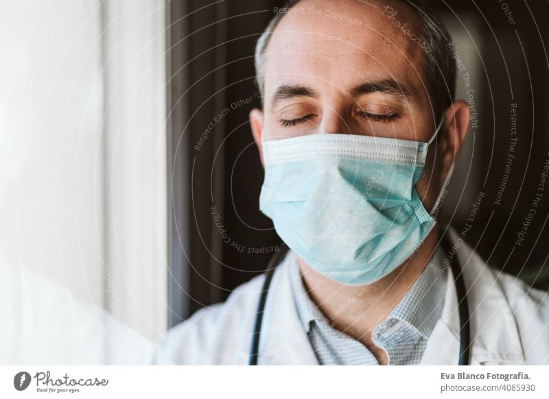 Porträt von Arzt Mann durch das Fenster tragen Schutzmaske und Handschuhe im Haus. Corona Virus Konzept professionell Corona-Virus Krankenhaus arbeiten