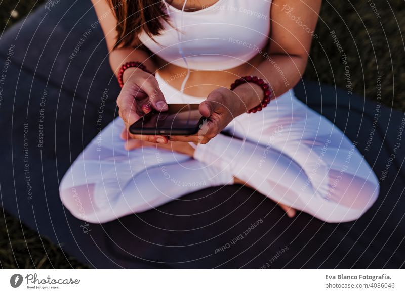 unerkennbar asiatische Frau entspannt nach ihrer Yoga-Praxis Musik hören auf Kopfhörer und Handy. Yoga und gesundes Leben Konzept jung Sommer Glück Genuss Sport