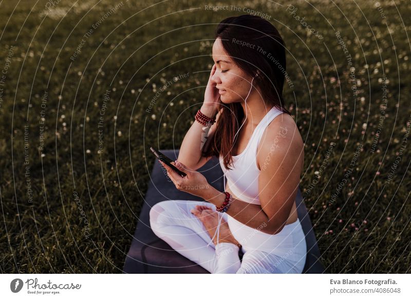 junge schöne asiatische Frau entspannt nach ihrer Yoga-Praxis Musik hören auf Kopfhörer und Handy. Yoga und gesundes Leben Konzept Sommer Glück Genuss Sport