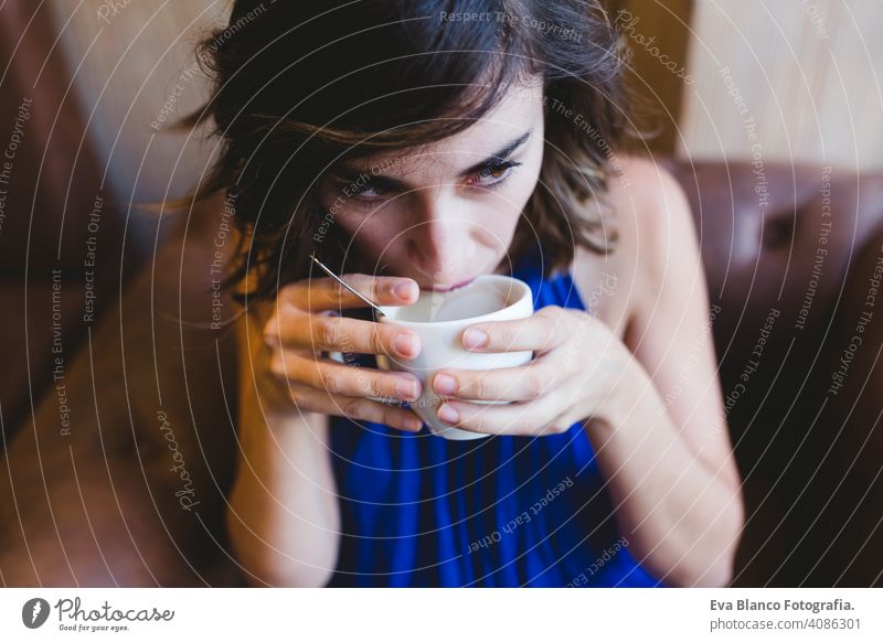 junge schöne Frau genießt eine Tasse Kaffee in einem Café. Laptop neben. Lässiges blaues Kleid. Modernes Leben im Innenbereich Morgen Beteiligung Schönheit