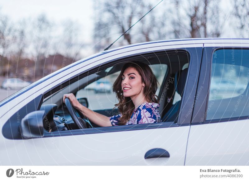 Junge Frau fährt ein Auto in der Stadt. Porträt einer schönen Frau in einem Auto, die aus dem Fenster schaut und lächelt. Reisen und Urlaub Konzepte