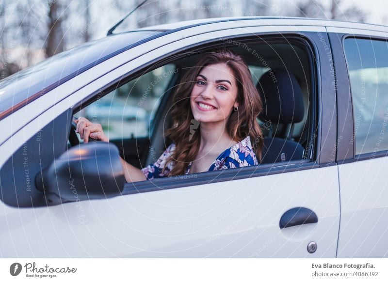 Junge Frau fährt ein Auto in der Stadt. Porträt einer schönen Frau in einem Auto, die aus dem Fenster schaut und lächelt. Reisen und Urlaub Konzepte