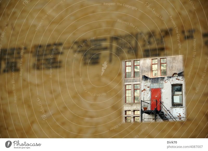 Blick durch den Bauzaun auf ein baufälliges Haus mit roter Tür in Brooklyn, New York Zaun Durchblick Öffnung Loch Guckloch Fassade Fabrik Fabrikhalle