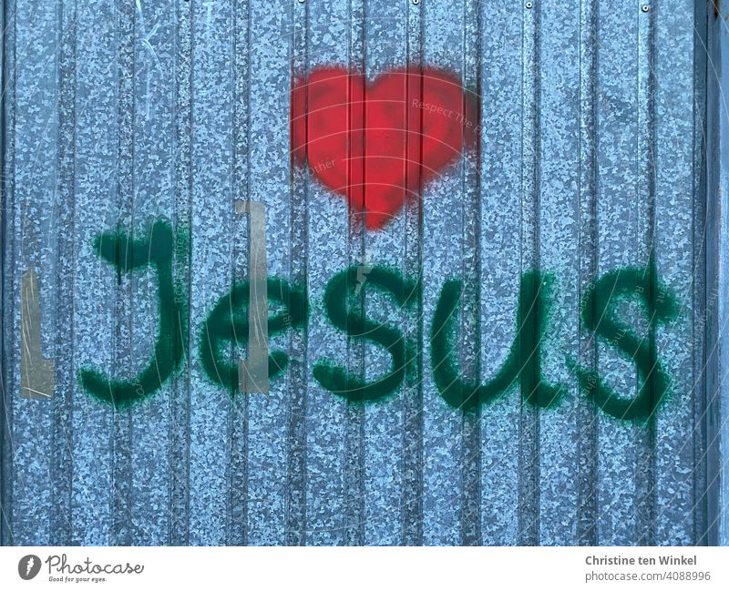 Graffiti mit dem Namen Jesus und einem roten Herz auf einer Metallfassade rotes Herz Liebe Metallwand Ostern Karwoche Glaube Hoffnung Kirche Jesus Christus