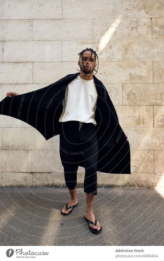 Trendy schwarzen Kerl posiert auf der Straße Mann posierend modisch dynamisch Bewegung Wand Model Hände in den Taschen Afroamerikaner Großstadt jung stylisch