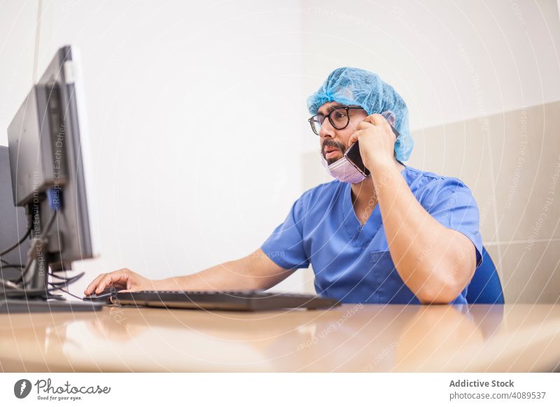 männlich Chirurgie am Computer und Smartphone arbeiten vor der Operation Erwachsener Krankenhaus medizinisch benutzend Kaukasier Arzt Medizin Büro Uniform