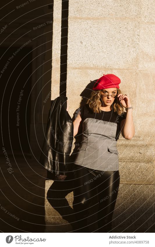 Stilvolle weibliche stehend in der Nähe von Gebäude Wand Frau stylisch Straße Großstadt in die Kamera schauen sinnlich sonnig tagsüber Lederjacke Baskenmütze