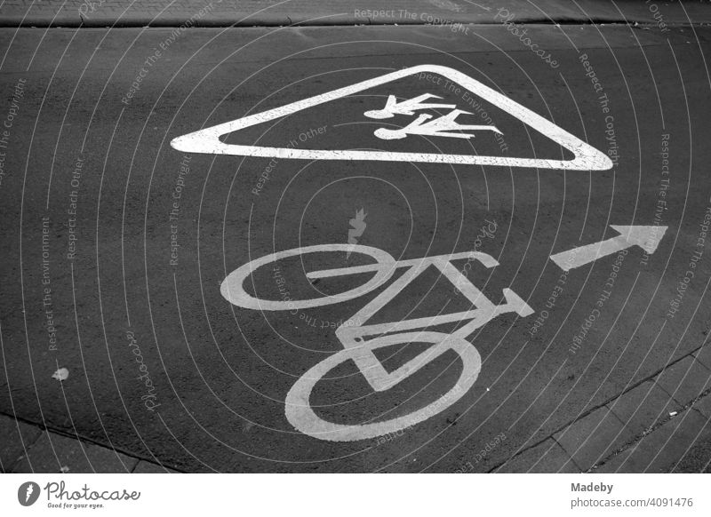Aufgemalter Hinweis für Autofahrer und Radfahrer auf Schulkinder auf grauem Asphalt im Mathildenviertel in Offenbach am Main in Hessen, fotografiert in neorealistischem Schwarzweiß