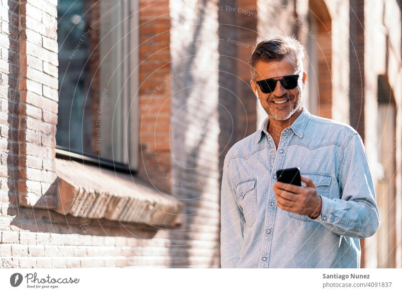 Geschäftsmann, der sein Smartphone auf der Straße benutzt. Mann Person Lifestyle Menschen mittleres Alter gutaussehend Senior im Freien Kaukasier Großstadt