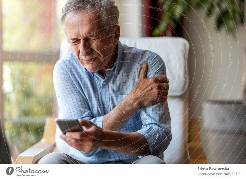Älterer Mann erleidet Schmerzen bei der Nutzung eines Smartphones zu Hause Senior älter Großvater alt Rentnerin in den Ruhestand getreten gealtert reif