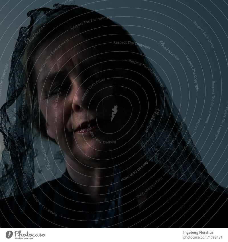 Verschleierte Frau teilweise im Schatten mit blauem/grauem Hintergrund Porträt Imkerschleier verschleiert Selbstportrait Kontemplation beschaulich traurig