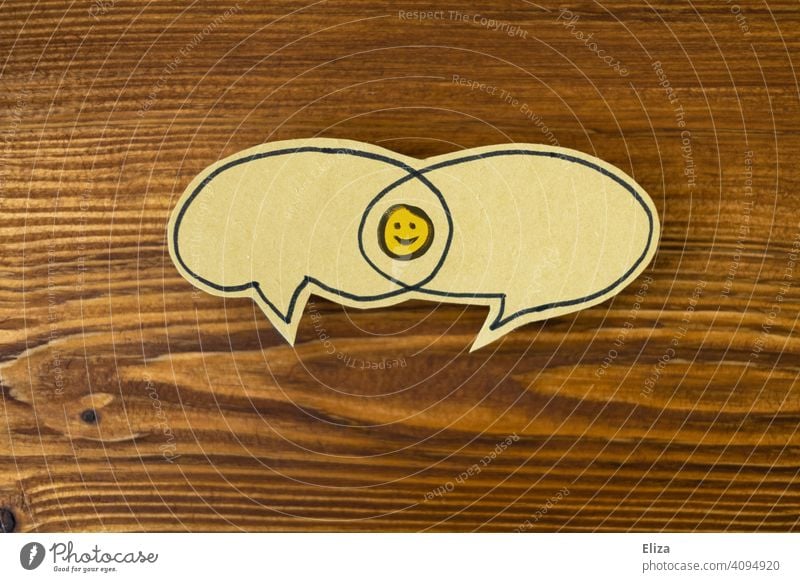 Zwei Sprechblasen mit einer Schnittmenge in der sich ein lachender Smiley befindet. Positive Kommunikation, Konsens und Einigkeit. Lösung positiv sprechen