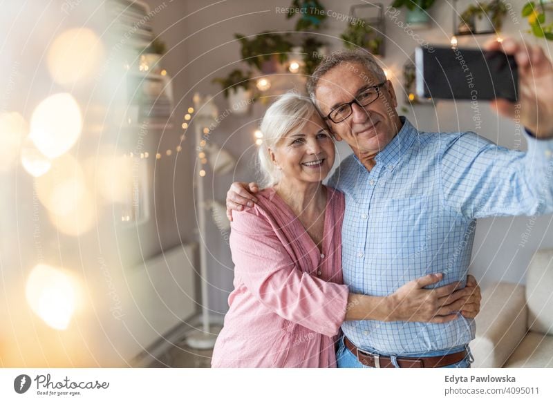 Senior Paar im Wohnzimmer nehmen Selfie mit Smartphone Menschen Frau Erwachsener reif lässig attraktiv männlich Mann Lächeln Glück Kaukasier zahnfarben