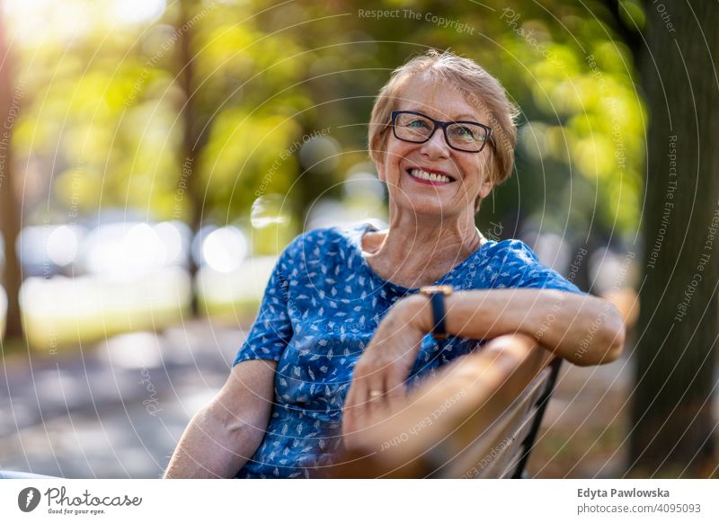 Porträt einer glücklichen älteren Frau, die auf einer Bank sitzt Menschen Senior reif lässig Kaukasier alt Großmutter Rentnerin Großeltern