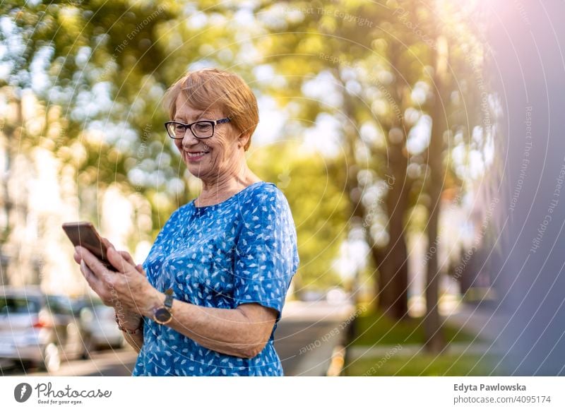 Porträt einer älteren Frau, die ein Mobiltelefon im Freien benutzt Menschen Senior reif lässig Kaukasier alt Großmutter Rentnerin Großeltern