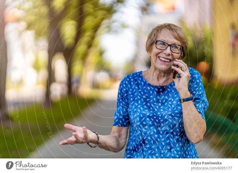 Porträt einer älteren Frau, die ein Mobiltelefon im Freien benutzt Menschen Senior reif lässig Kaukasier alt Großmutter Rentnerin Großeltern