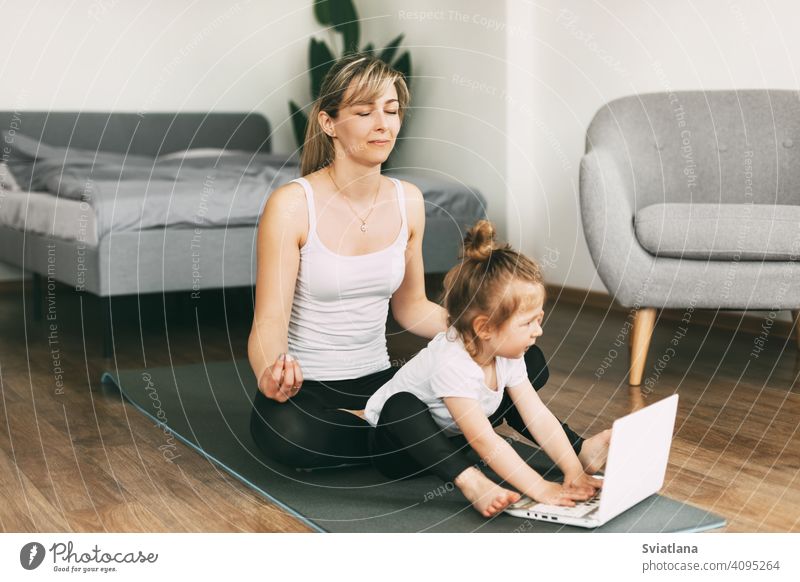 Eine schöne junge Frau und ihre bezaubernde kleine Tochter lächeln und meditieren nach einem gemeinsamen Workout Yoga Mama Meditation heimwärts Zusammensein