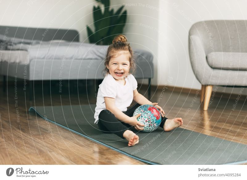 Ein kleines Kind spielt auf einer Sportmatte mit einem Ball Unterlage Gesundheit Baby Mädchen Kaukasier Spaß Kindheit Glück niedlich Lächeln Fitness Kleinkind