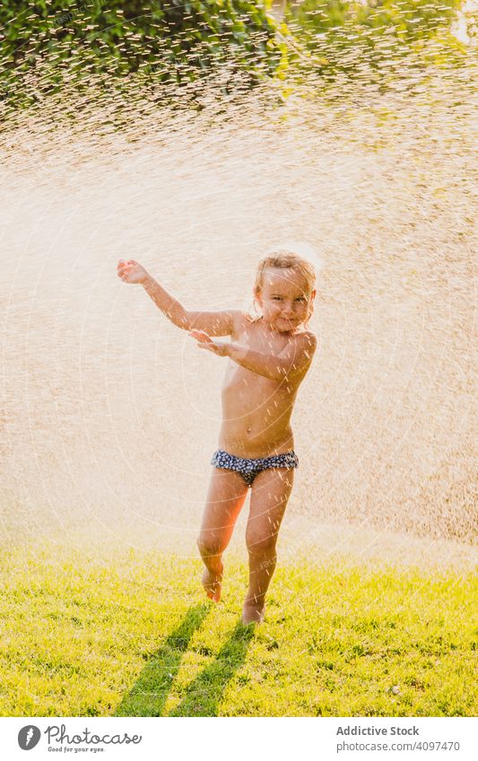 Mädchen ohne Hemd unter spritzendem Wasser im Garten spielen Spray Rasen Sommer sonnig tagsüber Spaß Kind wenig Frauenunterhose Kindheit Glück Freude Hof nass