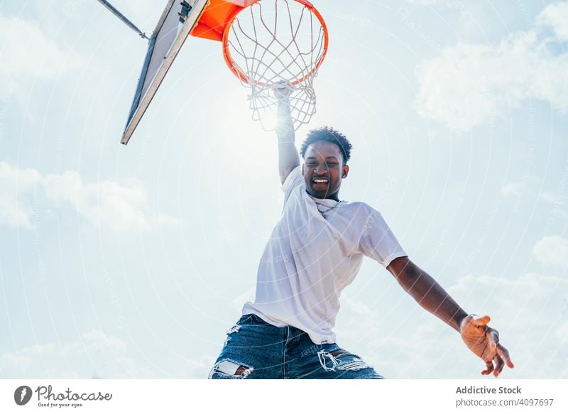 Afroamerikanischer Sportler hängt auf Basketball-Runde Ball tretend Netz Slam Dunk Spiel Spieler Stadion Spielen Sportbekleidung Aktivität Feld männlich