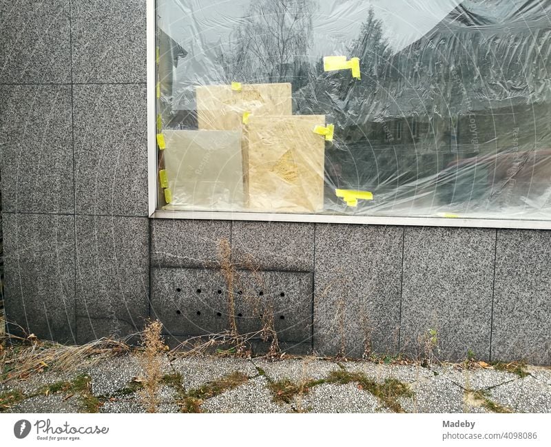 Von innen mit Folie verklebtes Schaufenster in grauer Fassade mit grauen Pflastersteinen in Oerlinghausen bei Bielefeld am Hermannsweg im Teutoburger Wald in Ostwestfalen-Lippe