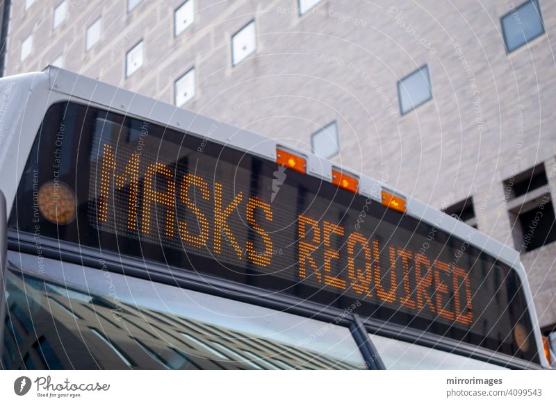 das vordere Dach eines Stadtbusses mit einem beleuchteten Schild mit der Aufschrift "Masken erforderlich" Corona-Virus Personenbus Transport Rabenvögel 19