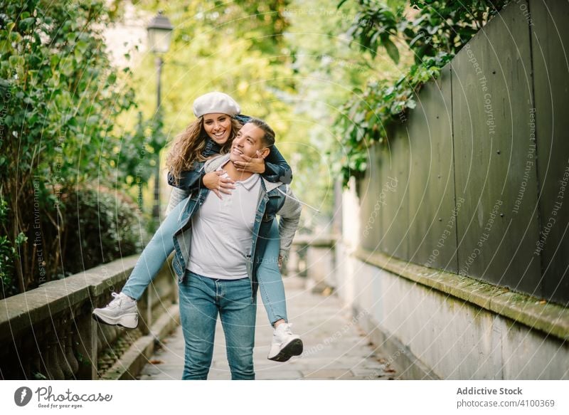 Glückliches Paar, das sich gemeinsam auf einer überwucherten Straße amüsiert laufen Küssen Spaß haben Ausgabenzine Frau Mann Sitzen Rücken Freizeit Sommer jung