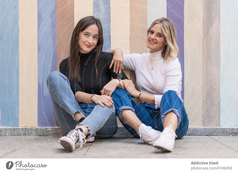 Glückliche Freundinnen Sitzen Vor Einer Bemalten Stadtmauer Ein Lizenzfreies Stock Foto Von 