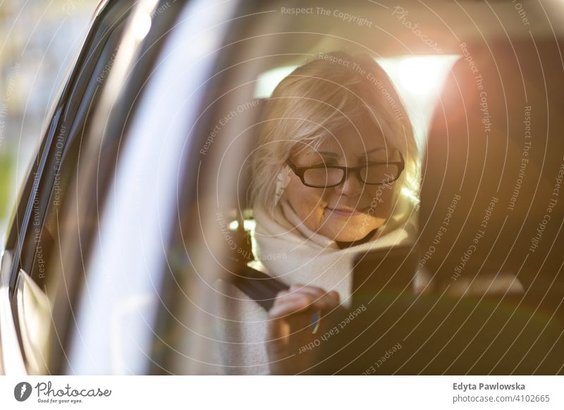 Ältere Frau mit Smartphone auf dem Rücksitz eines Autos Menschen eine Person Senior reif Rentnerinnen in den Ruhestand getreten alt älter graues Haar Kaukasier