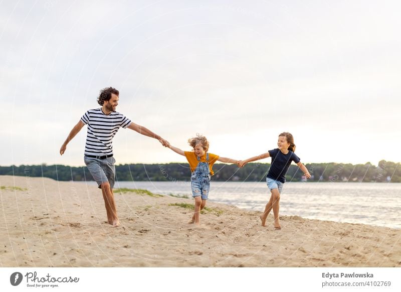 Vater mit zwei Kindern, die einen Tag am Strand genießen MEER See Feiertage Urlaub Natur Sommer Familie Eltern Sohn Junge Zusammensein