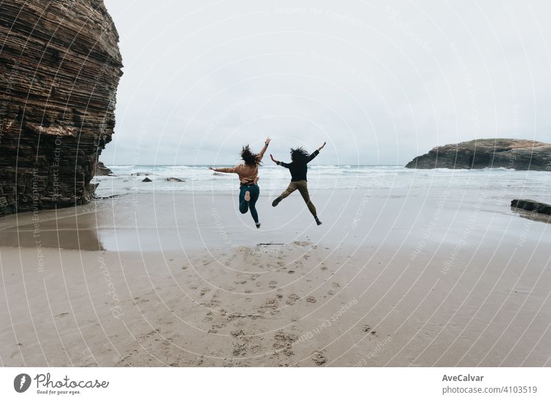Ein paar junge Frauen springen in einem wilden Strand mit Freiheit während eines sonnigen Tages mit Kopie Raum Glück springend Zusammensein Freundinnen zwei