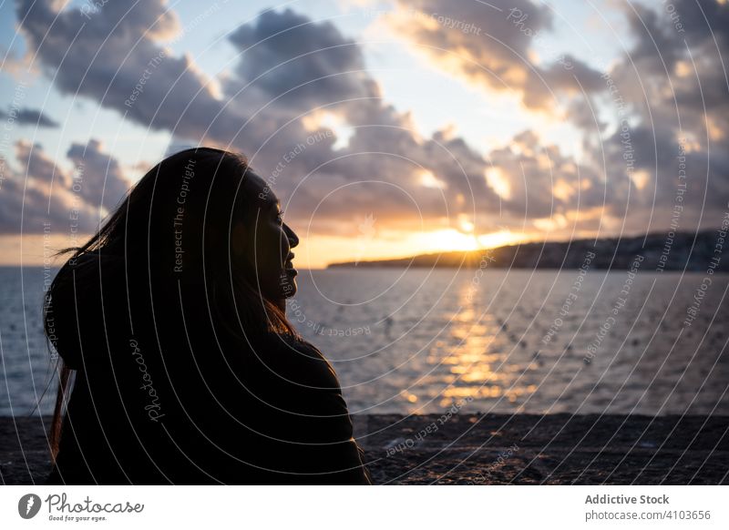 Fröhliche Frau im Urlaub in warmer Kleidung genießt den Sonnenuntergang am Meer Meeresufer Cloud Himmel Lächeln genießen Lachen Freude reisen Tourismus