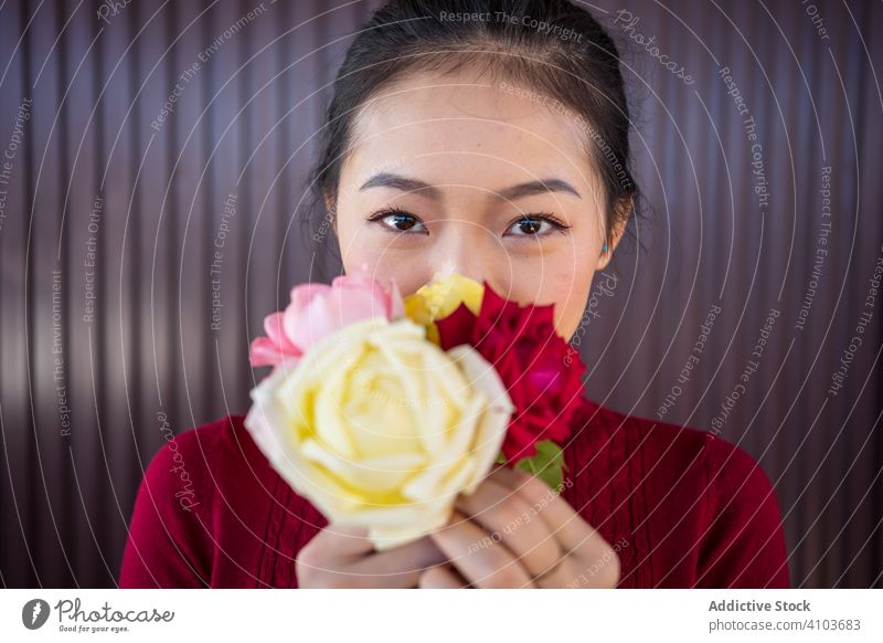 Asiatische Frau zeigt Rosenstrauß in die Kamera Blumenstrauß Lächeln Blumenhändler Roséwein asiatisch Pflanze ethnisch Chinesisch Japanisch jung Kultur grün