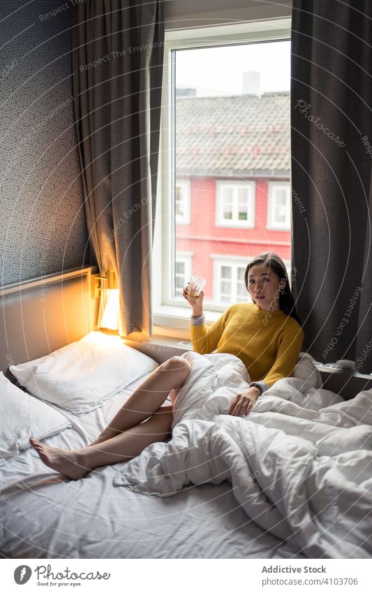 Frau trinkt Tee am Morgen Bett Sitzen Blick Fenster Ansicht Pullover trinken Kaffee Tasse heimwärts sich[Akk] entspannen Frühstück Getränk Becher heiß Lifestyle