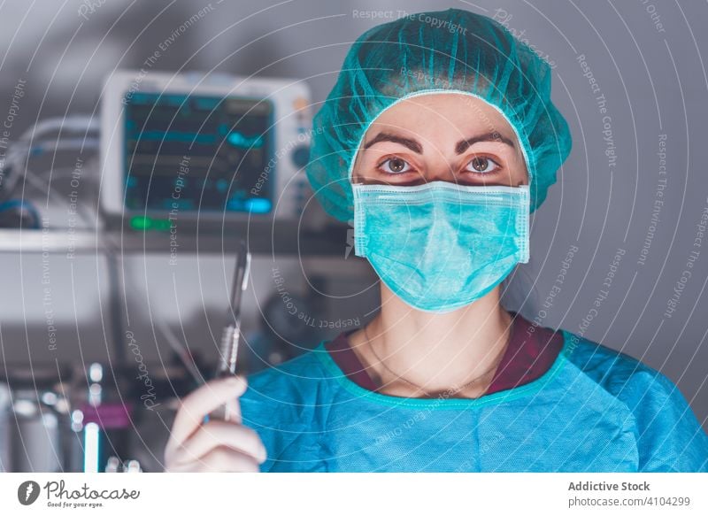 Weibliche Chirurgin im Operationssaal Krankenhaus Skalpell Mundschutz Hut bereit Frau Arbeit Arzt Gesundheitswesen stechend Lanzette steril Messer Werkzeug