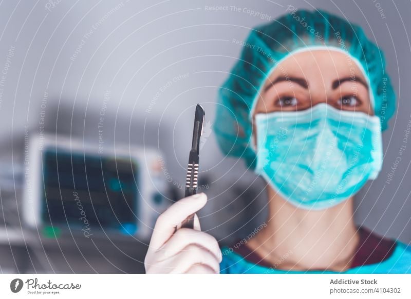 Weibliche Chirurgin im Operationssaal Krankenhaus Skalpell Mundschutz Hut bereit Frau Arbeit Arzt Gesundheitswesen stechend Lanzette steril Messer Werkzeug