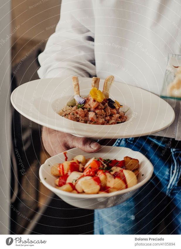 Restaurantkellner mit einer Portion pikanter spanischer Kartoffeln und einer Portion Lachstartar lokale Küche Gastronomie Snack Essen essen Lebensmittel