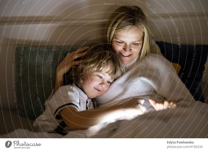 Mutter und Sohn verwenden digitale Tablette zusammen in der Nacht im Bett Schlafenszeit liegend digitales Tablett lesen Schlafzimmer Geschichtenerzählen