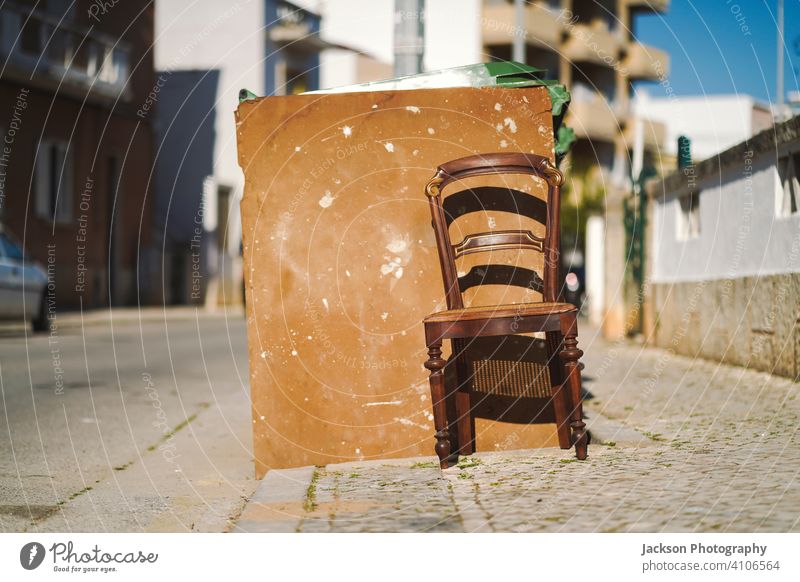 Vintage Holzstuhl neben Mülleimer auf der öffentlichen Straße Stuhl im Freien dreckig gepunktet gemalt Faro Portugal sonnig Kunst Verlassen vernachlässigt