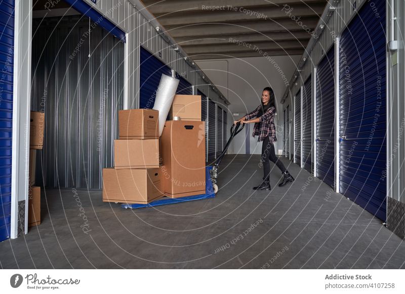 Frau bewegt Schubkarre mit Kisten Paket Lagerhalle Kurier Verpackung Ladung Verteilung Versand Transport sich[Akk] bewegen Arbeit Hypothek verlagernd bewegend