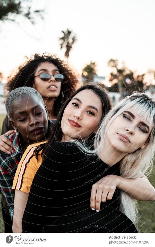 Multiethnische Gruppe von weiblichen Hipsterinnen, die mit jeder einzelnen kuscheln Menschengruppe Frauen Kuscheln jung Stil Lächeln Umarmung Porträt