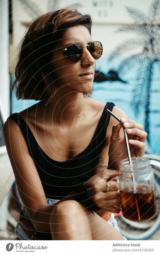 Fröhliche weibliche Reisende mit Sonnenbrille, die einen Cocktail trinkt Frau Resort tropisch Sommer räkeln heiter exotisch Tourismus sich[Akk] entspannen