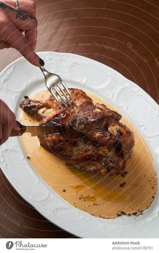 Unbekannte Frau schneidet gekochtes Huhn auf Teller geschnitten Hähnchen gegrillt Lebensmittel Abendessen Mahlzeit Fleisch Mittagessen frisch Messer Tisch