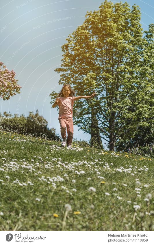 Porträt eines kleinen hispanischen Mädchens, das im Sommer im Park spielt und läuft. Genuss Hintergrund Tag spielen grün Freiheit offen Blume blasend Aktivität