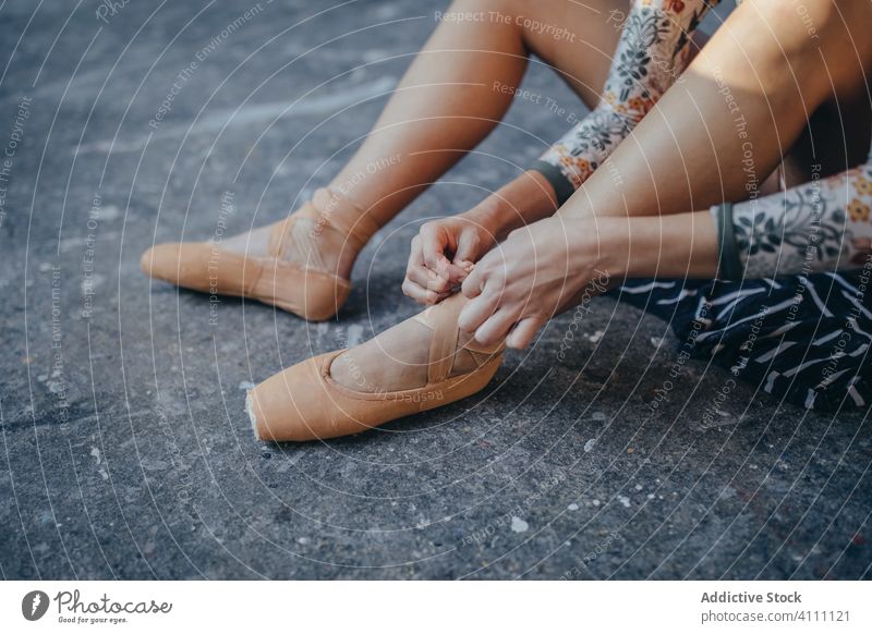 Frau sitzt auf dem Boden und zieht Ballettschuhe an Ballerina spitze Schuh Balletttänzer angezogen klassisch Tänzer Choreographie vorbereiten sitzen Stock