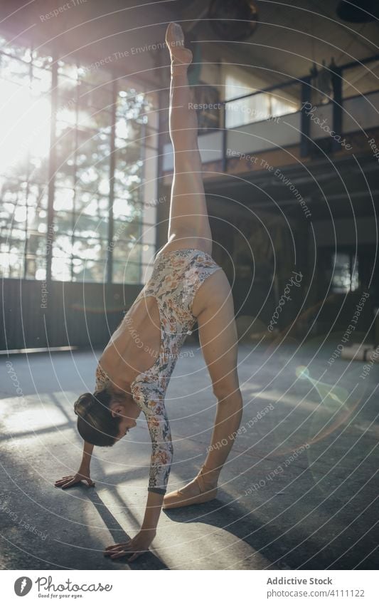 Junge Ballerina beim Training im sonnendurchfluteten Studio Frau Dehnung Übung Split Bein hoch üben beweglich Gleichgewicht ausführen passen gymnastisch Anmut