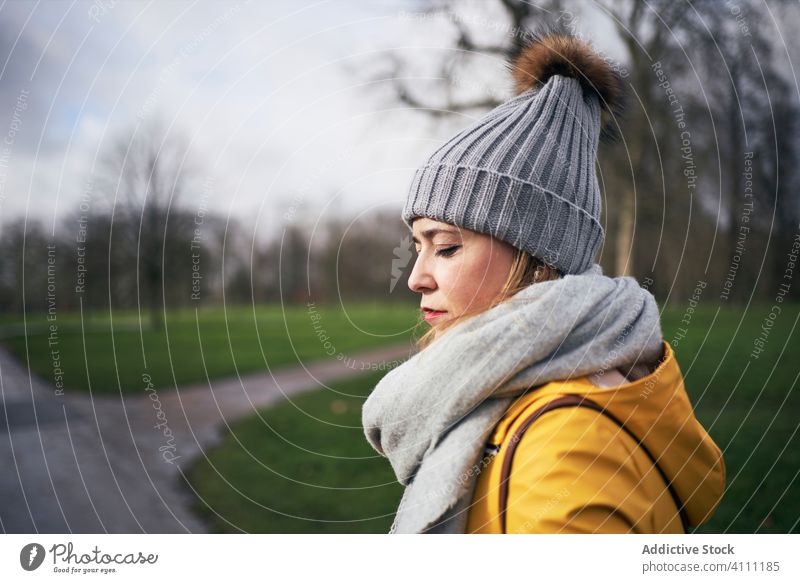 Frau in warmer Kleidung spaziert in düsterem Park warme Kleidung ruhig kalt allein schlendern trist Saison Gelassenheit friedlich Stil Herbst jung Hut Schal