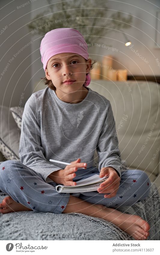 Konzentrierter kleiner Junge schreibt Notizen auf dem Bett schreiben Krebs Diagnostik Kind heimwärts Therapie männlich Kindheit treu sich[Akk] entspannen