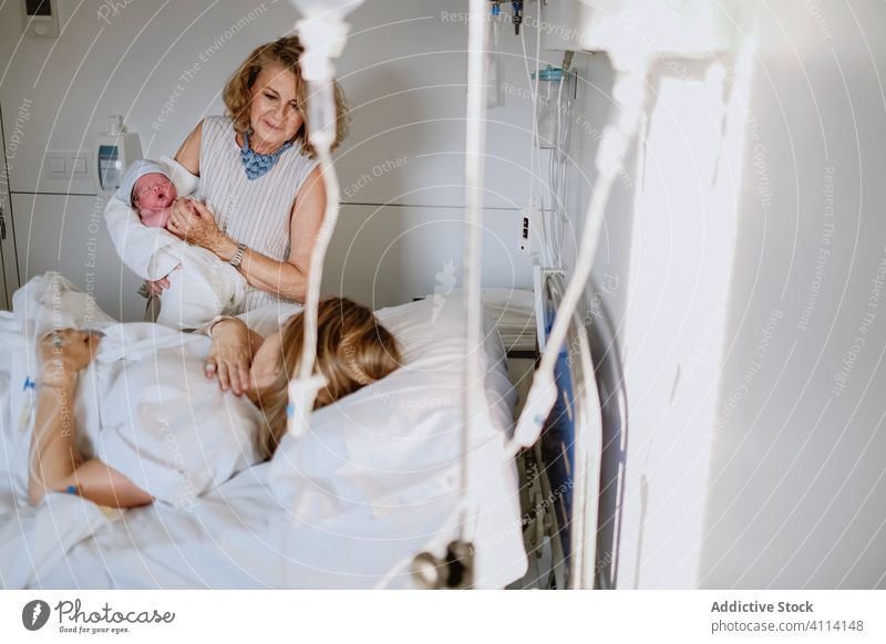 Frau besucht Tochter mit Neugeborenem im Krankenhaus neugeboren Baby Mutter Großmutter Frauen Pflege Bett besuchen Gruß Klinik Glück neonatal Kind Medizin
